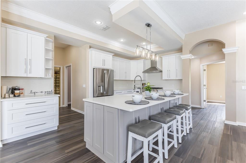 12230 Padron Boulevard Spring Hill, FL 34609 - Photo 6 of 22 a kitchen with stainless steel appliances kitchen island granite countertop a refrigerator a sink dishwasher a stove and white cabinets with wooden floor