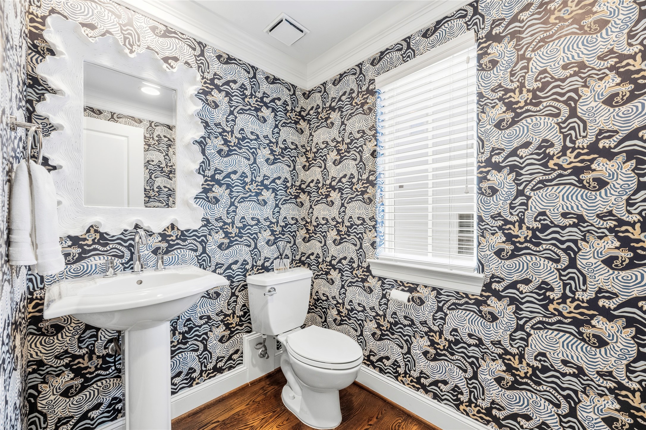 1537 Haddon Street Houston, TX 77006 - Photo 32 of 48 The half-bath on the second floorfeaturing bold patterned wallpaper with mythical creatures, a white pedestal sink, and a toilet (THIS HALF-BATH can be PAINTED if requested). The room is accented with a unique mirror, wooden flooring, and a window with blinds, offering a blend of contemporary and artistic elements.