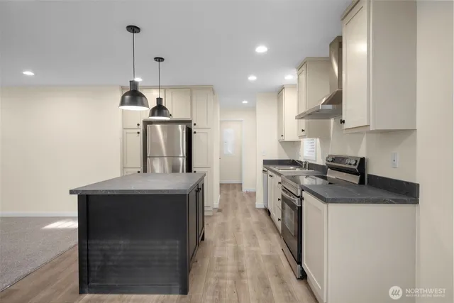 a kitchen with stainless steel appliances granite countertop a sink a stove and a refrigerator