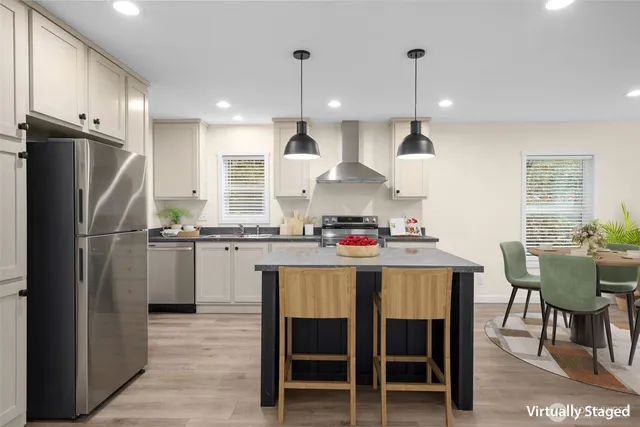 a kitchen with stainless steel appliances granite countertop a sink a stove a refrigerator and chairs