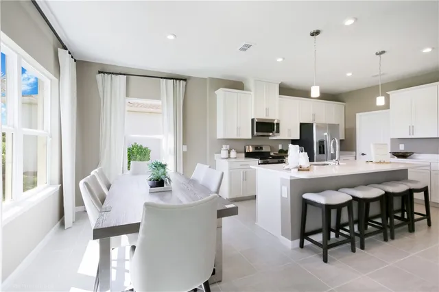 a kitchen with microwave a refrigerator and chairs