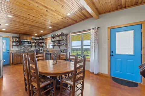 a kitchen with stainless steel appliances kitchen island granite countertop a table chairs and a refrigerator