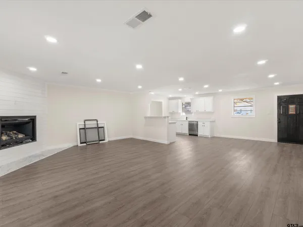 a view of an empty room with wooden floor and a fireplace