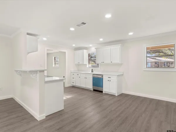 a kitchen with white cabinets sink and dishwasher with wooden floor