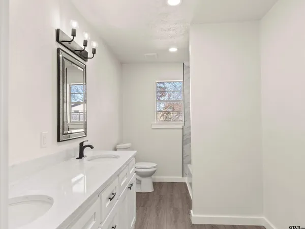 a bathroom with a tub sink vanity granite and shower