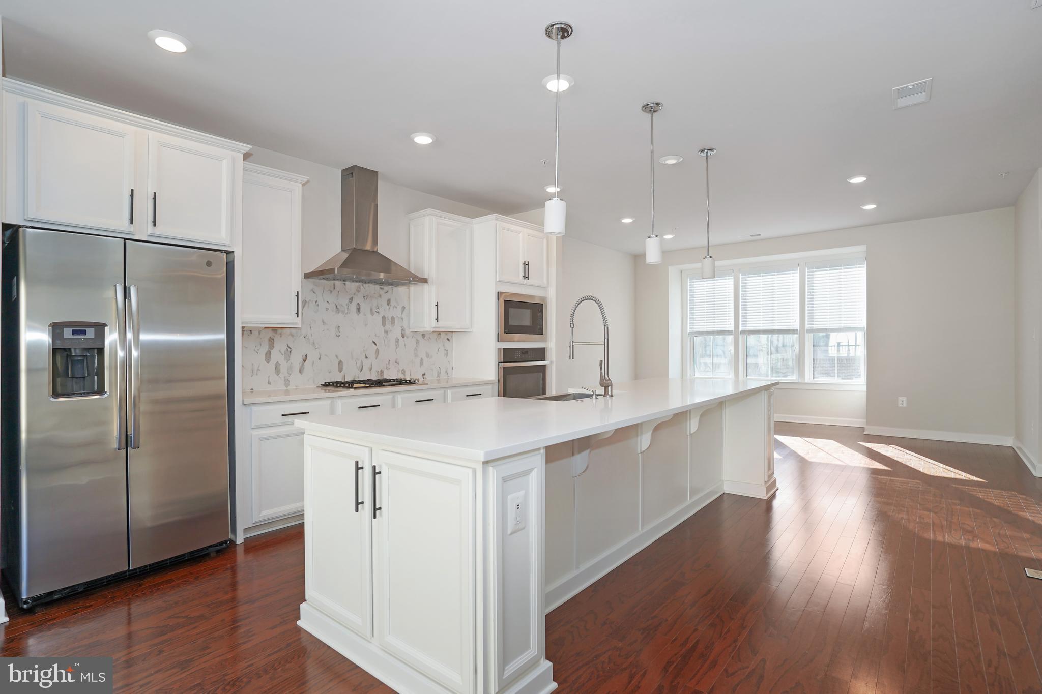 a large kitchen with stainless steel appliances kitchen island a large counter top and a refrigerator