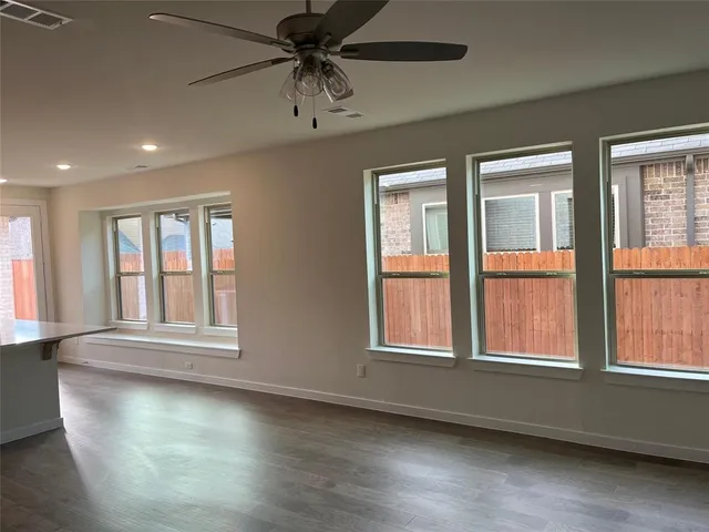 an empty room with wooden floor fan and windows