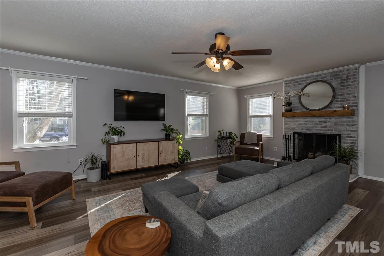 3628 Wickersham Way Raleigh, NC 27604 - Photo 10 of 21 a living room with furniture a flat screen tv and a fireplace