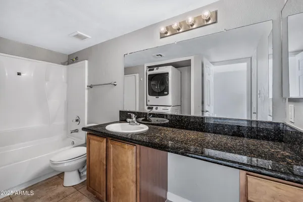 a bathroom with a granite countertop sink a toilet a mirror and bathtub