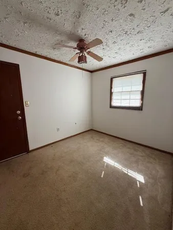 an empty room with a ceiling fan and window