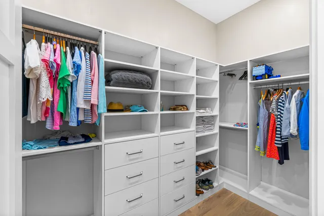 a view of walk in closet with clothes and shoes