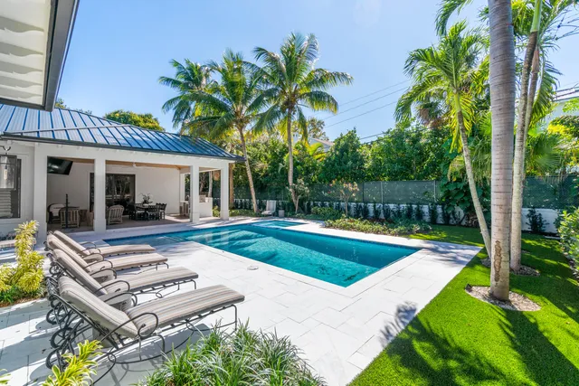 a view of a house with swimming pool lawn chairs and a yard