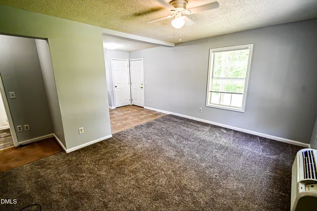 an empty room with windows and fan
