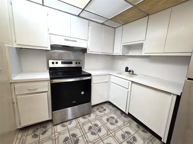 a kitchen with white cabinets and appliances