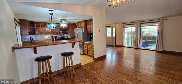 a kitchen with stainless steel appliances granite countertop a refrigerator a stove and a sink with wooden floor