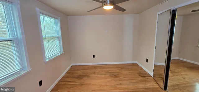a view of empty room with wooden floor and fan