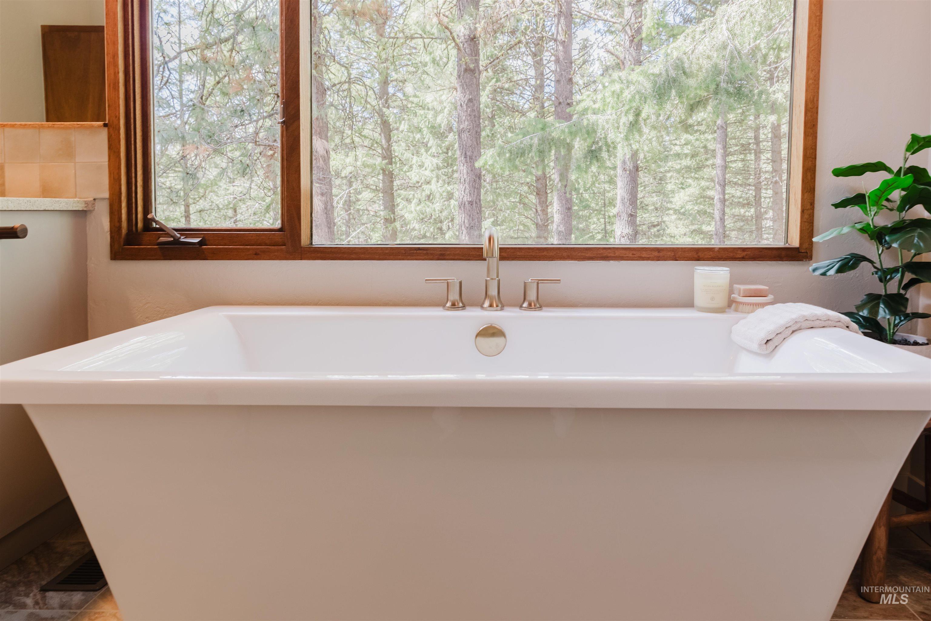 136 Silver Fox Trail McCall, ID 83638 - Photo 17 of 31 Freestanding soaking tub with gold-finish fixtures and a large window showcasing surrounding trees