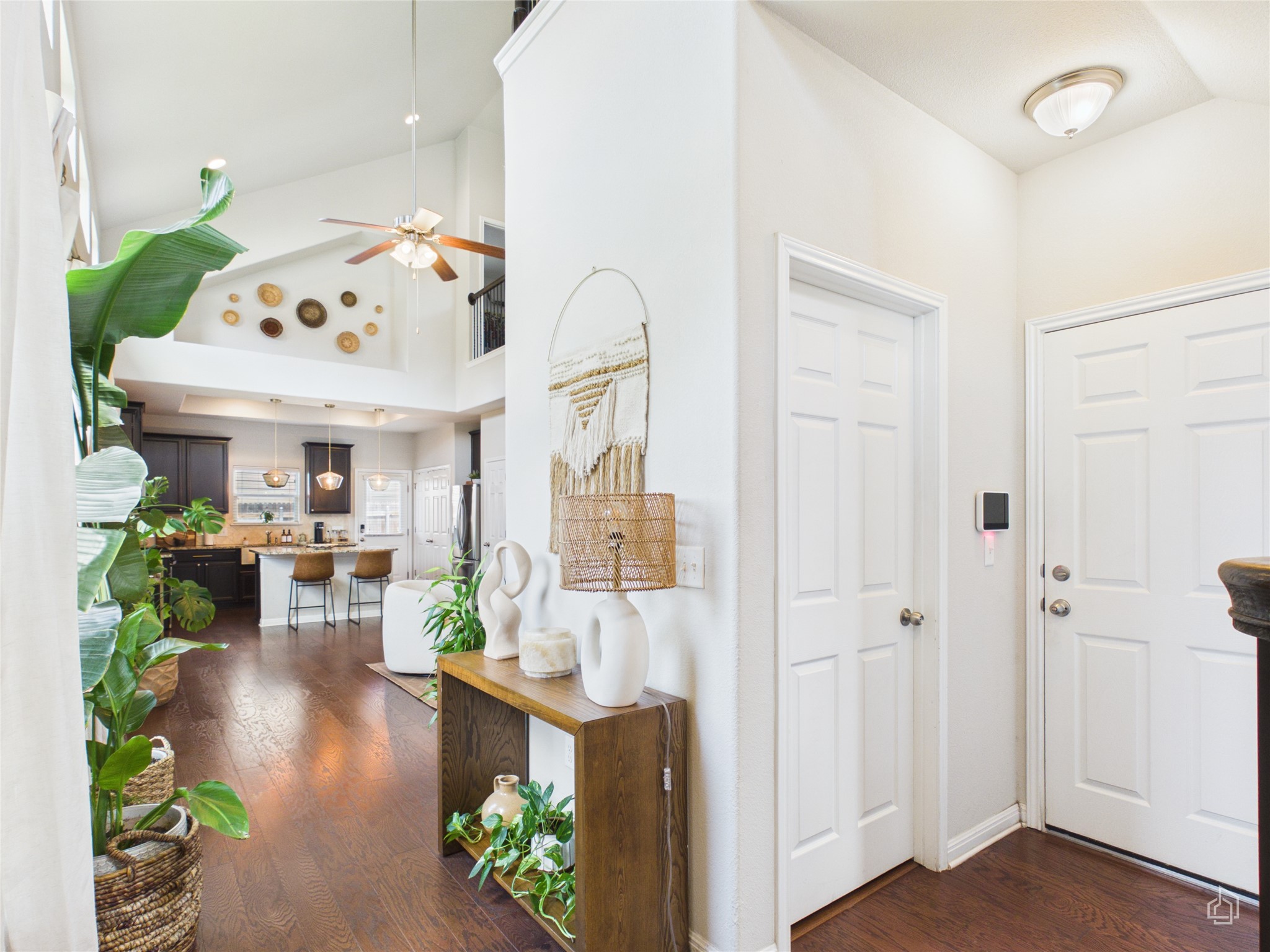 9310 Tanager Way Austin, TX 78748 - Photo 2 of 32 A spacious foyer opens to a well-lit kitchen, featuring high ceilings and dark hardwood flooring.