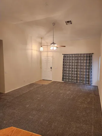 a view of an empty room with a chandelier fan