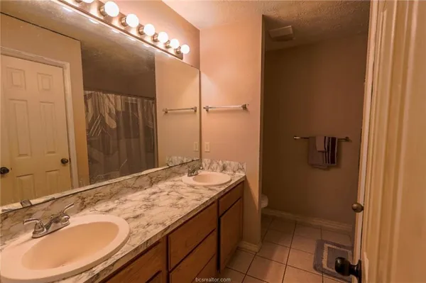 a bathroom with a granite countertop sink a mirror and a shower
