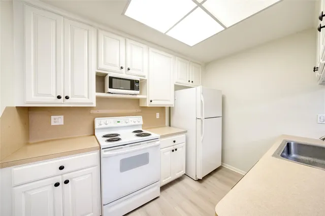 a view of a kitchen with a fridge and wooden floor