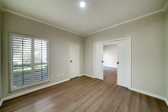a view of an empty room with wooden floor fireplace and a window