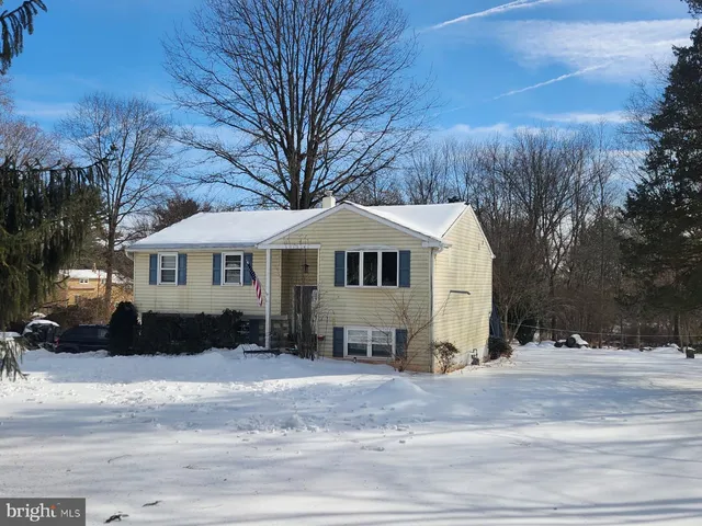 a front view of a house with a yard covered with snow and trees