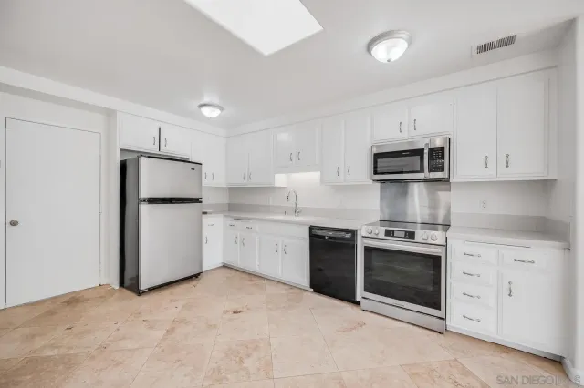 a kitchen with stainless steel appliances granite countertop white cabinets a refrigerator a stove a microwave and a sink