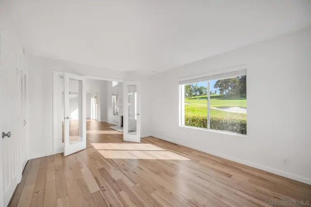 a view of empty room with wooden floor and fan