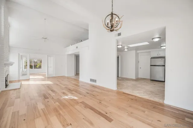 a view of a livingroom with wooden floor and a kitchen