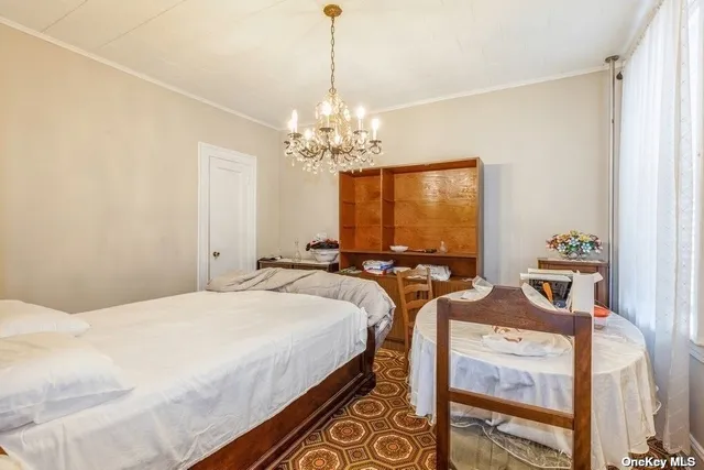 a bedroom with bed a chandelier and a window