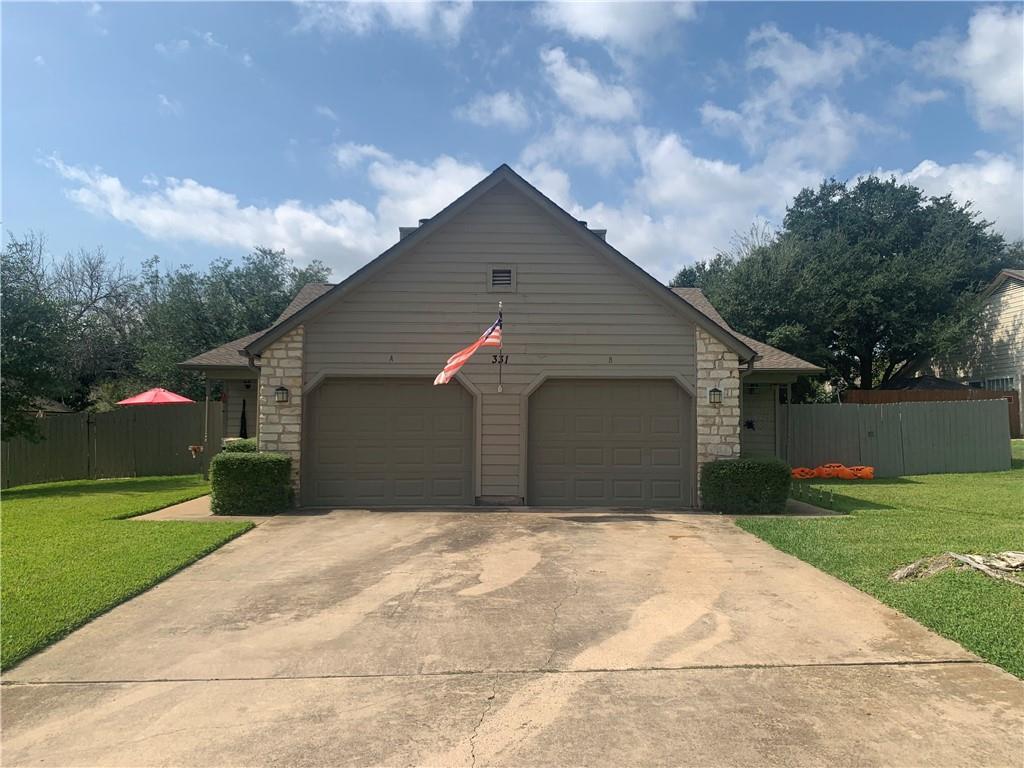 View of side of property with stone siding, a garage, and concrete driveway