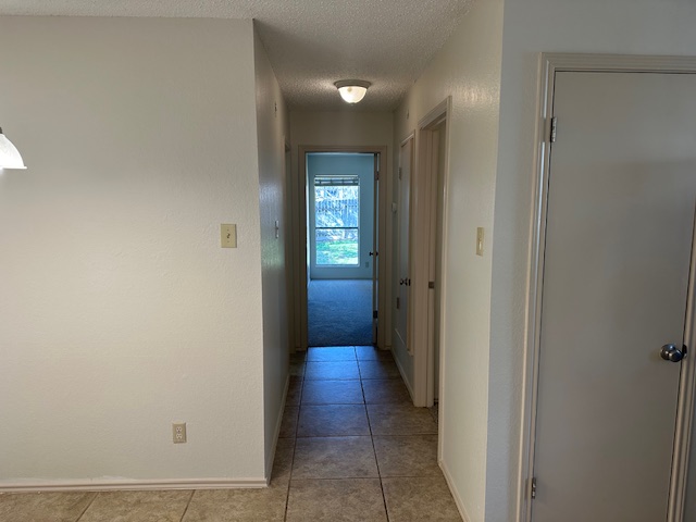 331 Fantail Loop, Unit B Austin, TX 78734 - Photo 11 of 16 Hallway featuring a textured ceiling, light tile patterned flooring, and a textured wall
