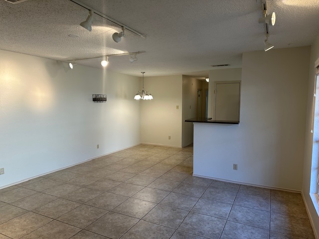 331 Fantail Loop, Unit B Austin, TX 78734 - Photo 7 of 16 Empty room with a textured ceiling, a chandelier, and light tile patterned flooring