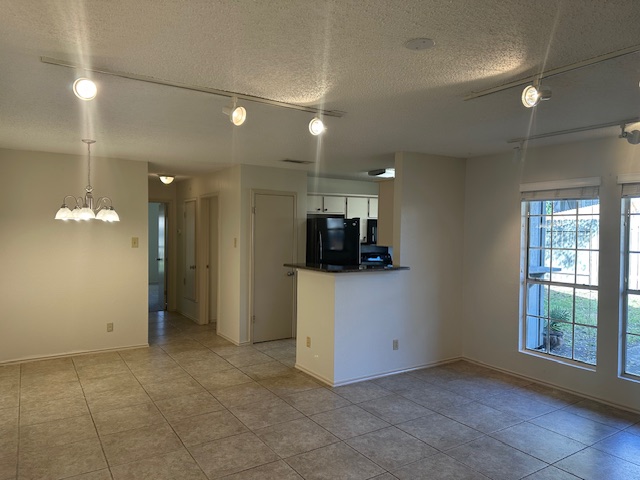 331 Fantail Loop, Unit B Austin, TX 78734 - Photo 8 of 16 Kitchen with white cabinets, a textured ceiling, freestanding refrigerator, hanging lights, and dark countertops