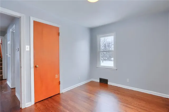an empty room with wooden floor and a window