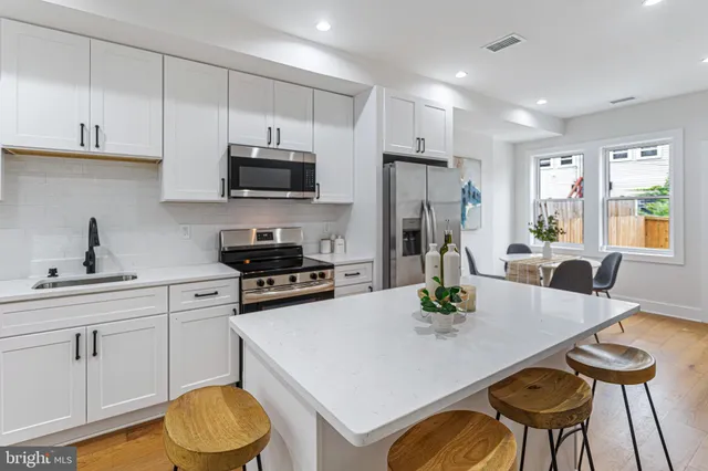 a kitchen with stainless steel appliances a stove a sink a microwave a dining table and chairs