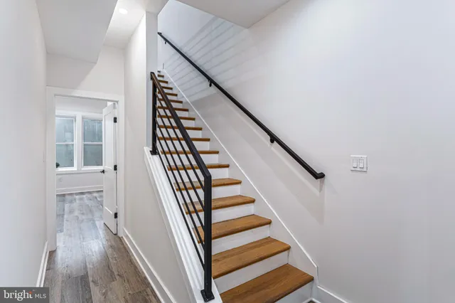 a view of staircase with wooden floor and white walls