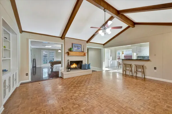 a room with wooden floor pool table and chairs