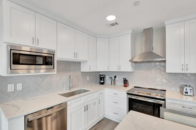 a kitchen with stainless steel appliances white cabinets and a stove a oven with white countertops