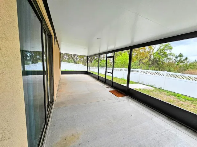 a view of an empty room with wooden floor and windows