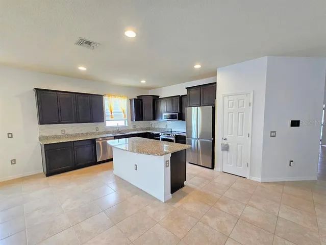 a large kitchen with a large counter top stainless steel appliances and cabinets