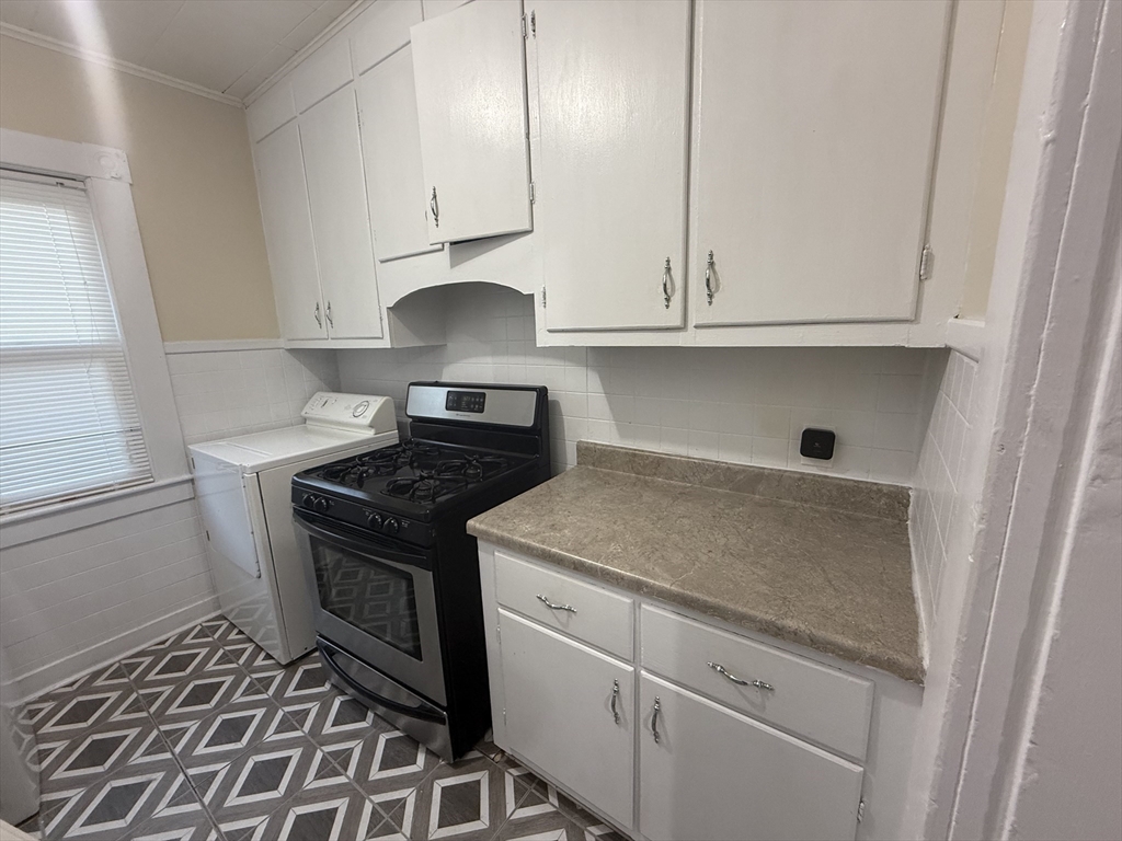 32 Manchester Street, Unit 1 Lowell, MA 01852 - Photo 3 of 8 a kitchen with granite countertop white cabinets and white appliances