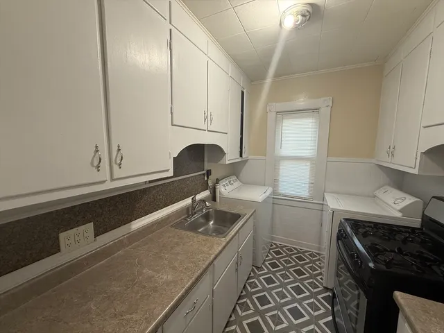 a kitchen with granite countertop a sink a stove and cabinets
