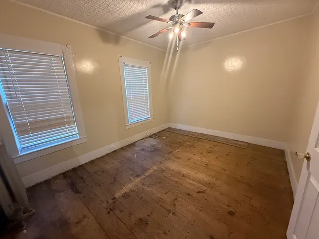 an empty room with windows and fan