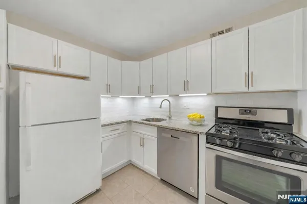 a kitchen with stainless steel appliances white cabinets sink and a refrigerator