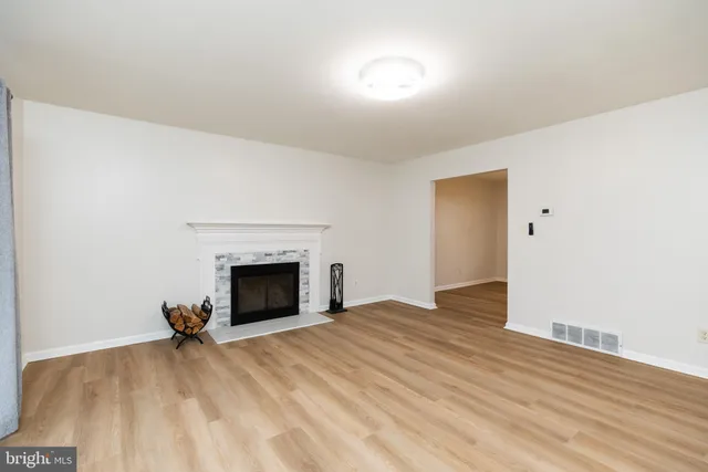 a view of empty room with wooden floor and fireplace