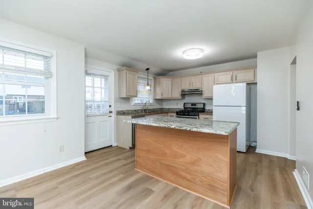 a kitchen with granite countertop a refrigerator stove top oven and sink