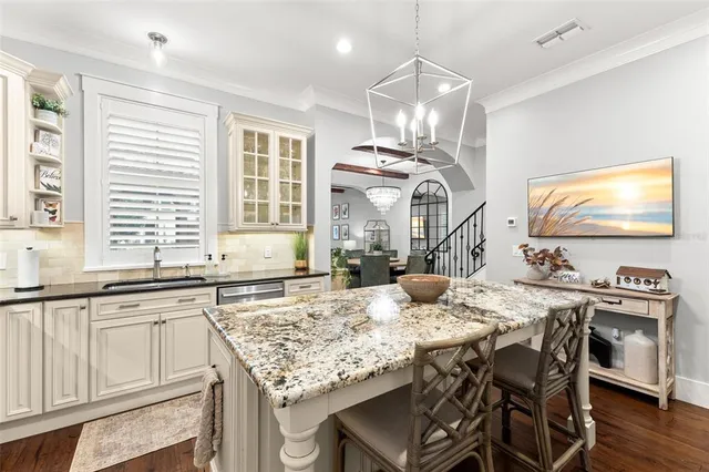 a kitchen with kitchen island granite countertop a table chairs sink and cabinets