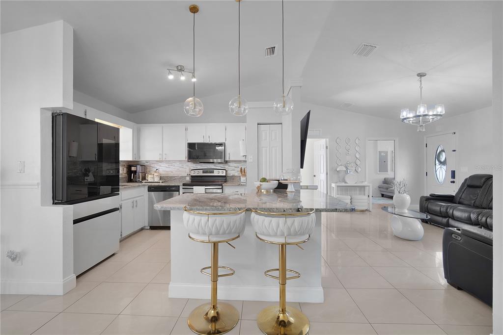16285 Southwest 21st Court Ocala, FL 34473 - Photo 7 of 40 a kitchen with stainless steel appliances kitchen island granite countertop a stove a sink a kitchen island a stove a dining table and chairs